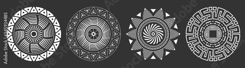 Set of four abstract circular ornaments. Decorative patterns isolated on black background. Tribal ethnic motifs. Stylized sun symbols. Stencil tattoo and prints Vector monochrome illustration. photo