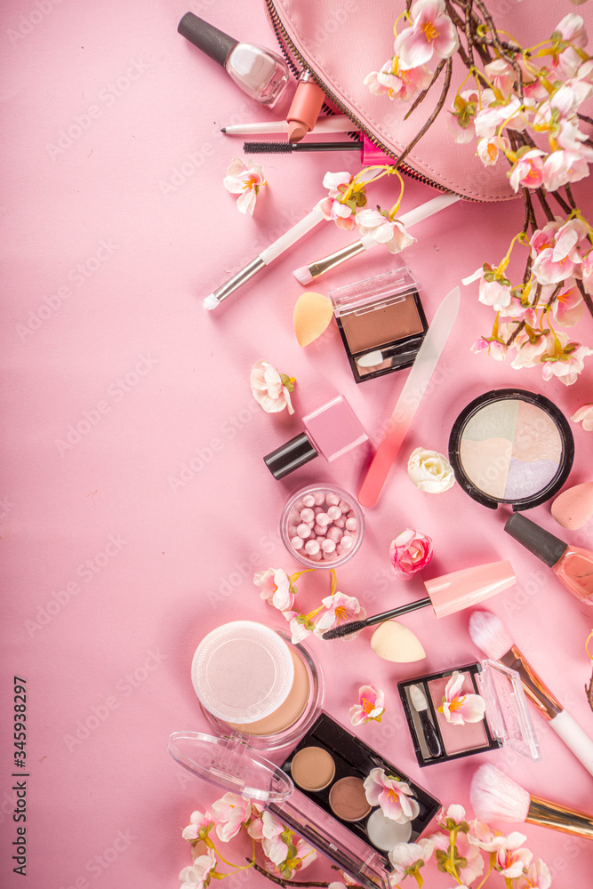Fototapeta Makeup products with cosmetic bag and spring flowers. Professional Makeup set flatlay. Set of decorative cosmetics on tender pink background. Copy space above