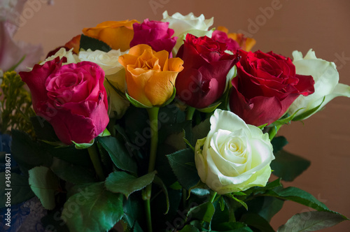 Lovely big colorful bouquet with many flowers  roses of red  vinous  orange and white colors. Green leaves and thorns. Still life. Calm pink background