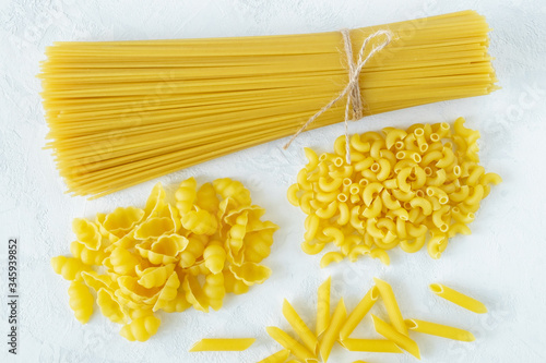 Dry raw several types of pasta on a light background. Healthy eating, Italian kitchen concept. Horizontal orientation, top view, selective focus.