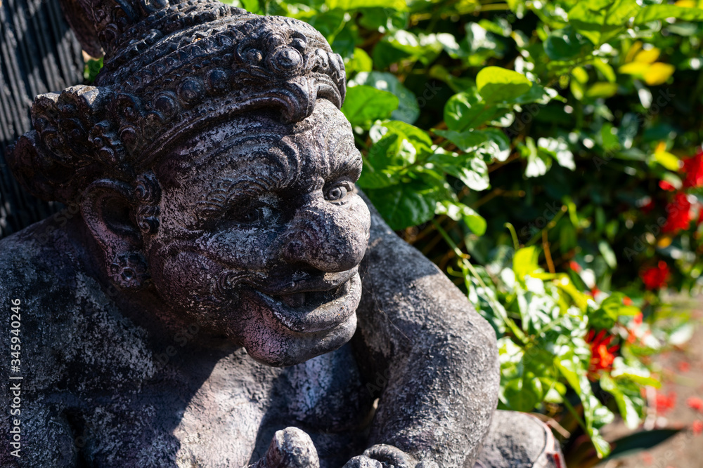 Balinese stone statue against the blue sky and trees