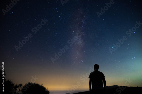 Blurred silhouette of a man observing the starry sky with the milky way