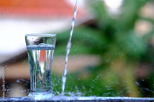 Close up pouring purified fresh drink water from the bottle on wood counter and space for text