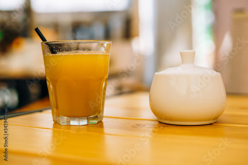 Glass of orange juice on a wooden table. White sugar bowl and a glass of fruit juice. Fresh healthy juice in a glass on a table in a cafe