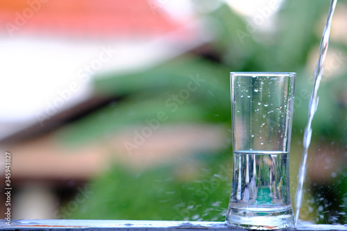 Close up pouring purified fresh drink water from the bottle on wood counter and space for text