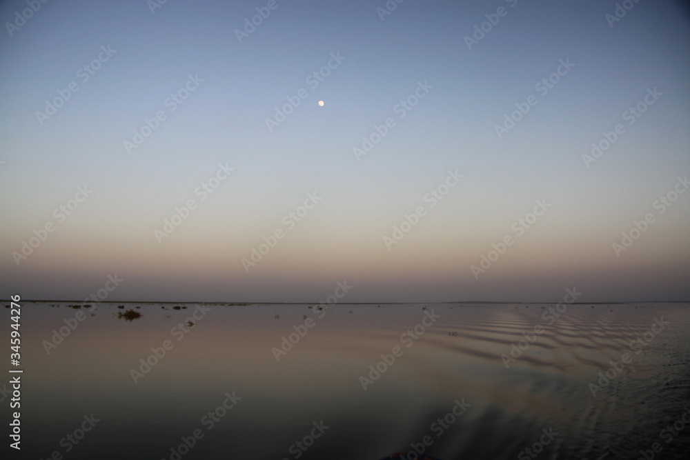 Malowniczy wschód księżyca w pełni na gładkim niebie nad spokojnymi wodami rzeki Niger - obrazy, fototapety, plakaty 