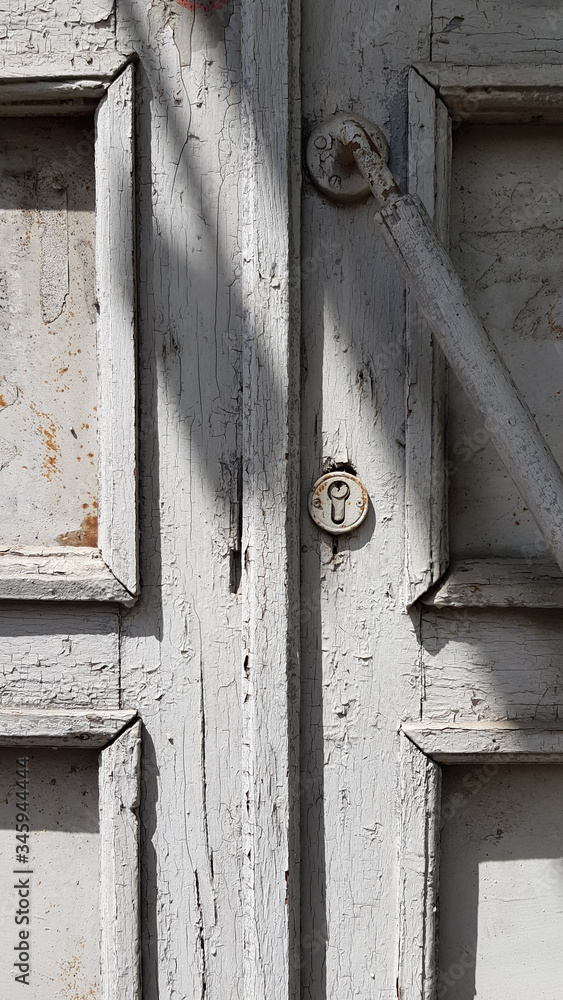 old wooden door with metal handle. Rough texture of old wooden door. Entrance to shabby door of abandoned building