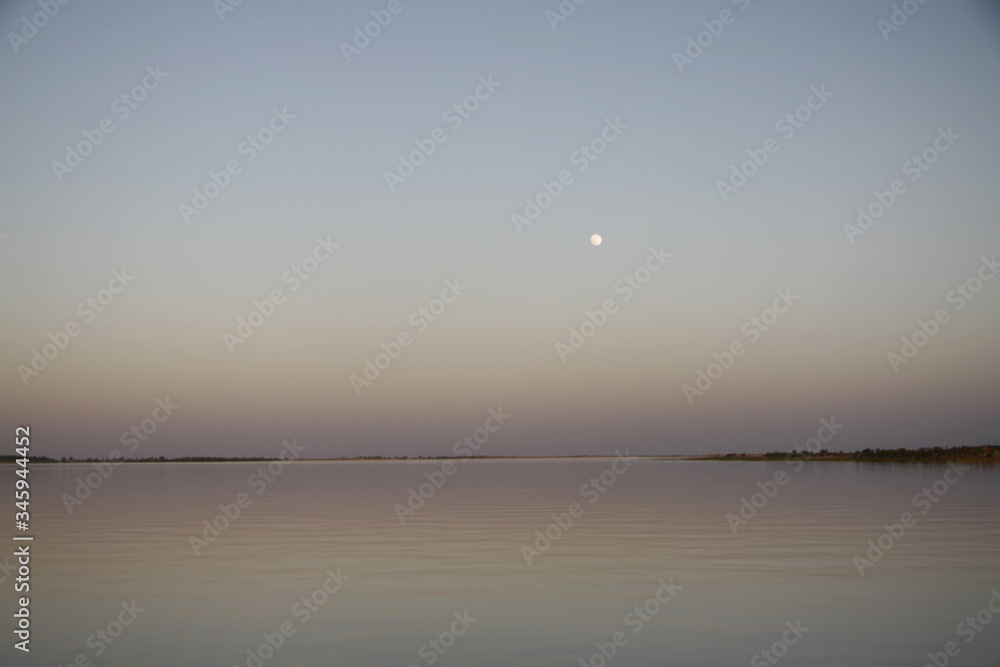 Malowniczy wschód księżyca w pełni na gładkim niebie nad spokojnymi wodami rzeki Niger - obrazy, fototapety, plakaty 