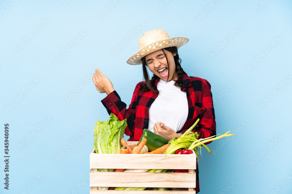 Young farmer Woman holding fresh vegetables in a wooden basket making guitar gesture
