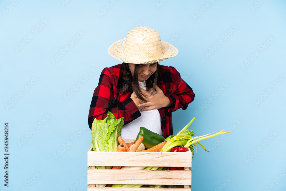 Young farmer Woman holding fresh vegetables in a wooden basket having a pain in the heart