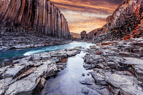  Wonderful Nature landscape. Incredible view on river in canyon with black basalt columns under sunlight, Tipical Icelandic scenery. Studlagil Canyon during sunset. Iconic location for photographers.