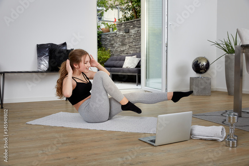 Teenager macht Sport Zuhause im Wohnzimmer und trainiert ihre Bauchmuskeln und macht Situps 