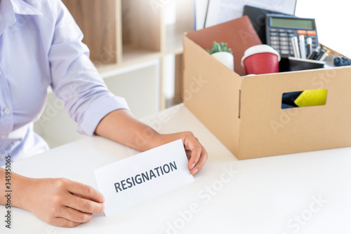 Stress of business woman packing brown cardboard box her belonging after resign and signing cancellation contract letter, Change of job unemployment or resignation concept.
