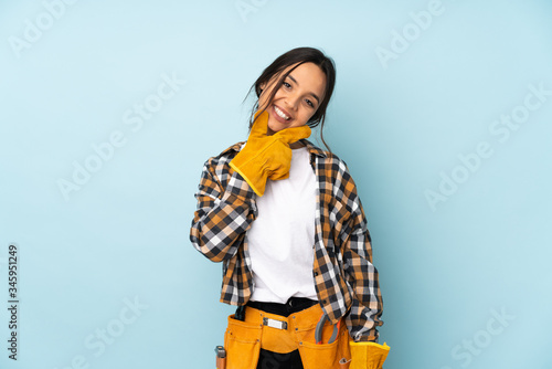Young electrician woman isolated on blue background smiling
