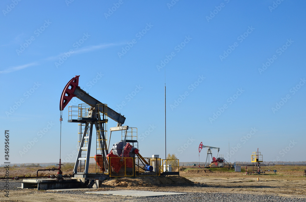Oil drilling derricks at desert oilfield for fossil fuels output and crude oil production from the ground. Oil drill rig and pump jack. Oil drilling derricks at desert oilfield for fossil fuels output and crude oil production from the ground. Oil drill rig and pump jack.