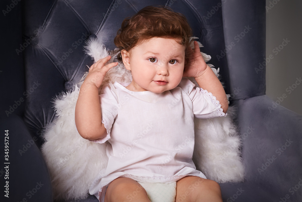 Little boy like angel smile and sit on luxurious violet armchair. Toddler boy in angel wings in baroque style interior room. international children's day. Little boy like angel smile and sit on luxurious violet armchair. Toddler boy in angel wings in baroque style interior room. international children's day.