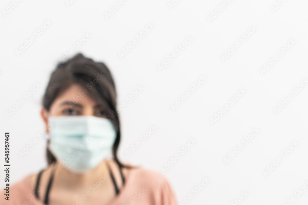 Blurred background woman with mask. White background with blurred woman wearing a surgical mask. Concept for covid-19 coronavirus banner and backdrop. Blurred background woman with mask. White background with blurred woman wearing a surgical mask. Concept for covid-19 coronavirus banner and backdrop.