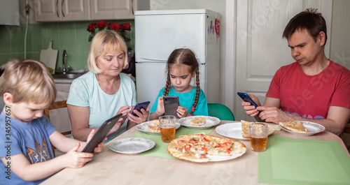 Big multi-generation family having dinner together, but everyone is texting in his own smartphone