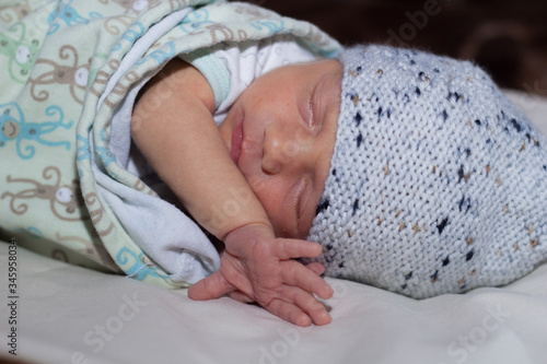 a newborn baby lies on a sofa in a hat stuck out one handle. Newborn is resting and sleeping comfortably