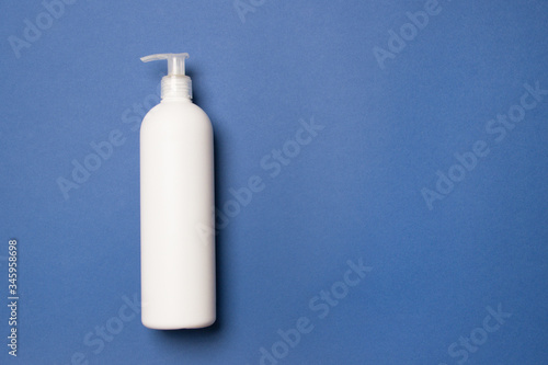 yellow bottle with cleaning agent on blue colored paper background with copy space