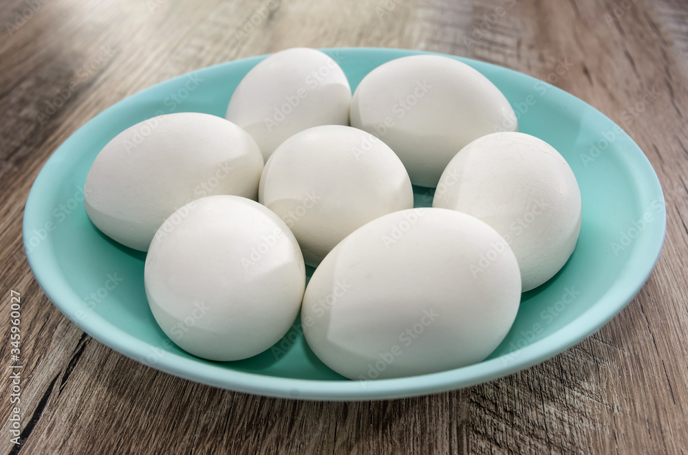 white chicken eggs in a plate on a wooden background. Close-up. white chicken eggs in a plate on a wooden background. Close-up.