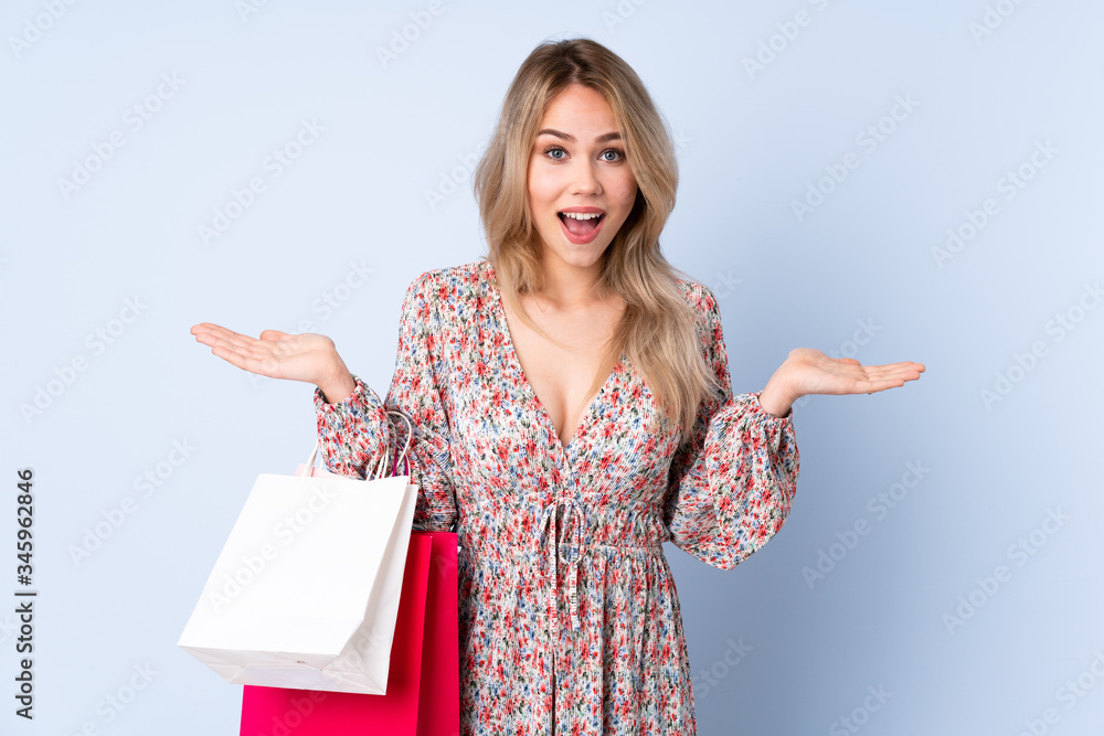 Teenager Russian girl with shopping bag isolated on blue background with shocked facial expression Teenager Russian girl with shopping bag isolated on blue background with shocked facial expression