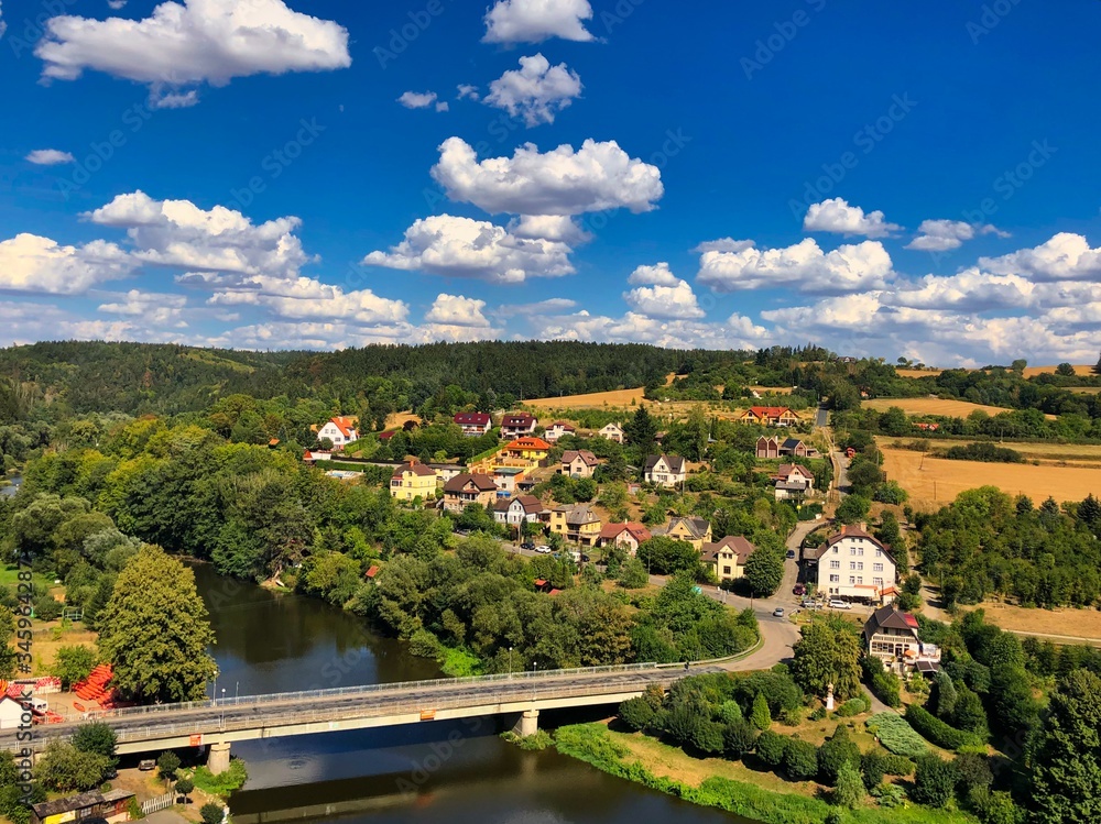 A colorful photo view of a village with some clouds on a blue sky, Sazava river and bridge taken from a Cesky Sternberk caste in Czech Republic