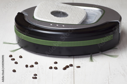 Automatyczny odkurzacz na białych panelach podłogowych, który sprząta ziarna kawy i inne zanieczyszczenia wymagające codziennego czyszczenia.

