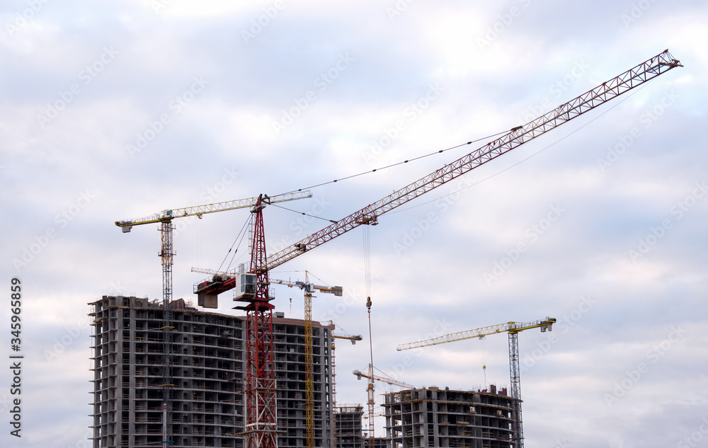 Tower cranes at large scale construction site against blue sky. Construction crane. Formwork solutions for reinforced construction and framed superstructure. Сoncept of renovation of new housing Tower cranes at large scale construction site against blue sky. Construction crane. Formwork solutions for reinforced construction and framed superstructure. Сoncept of renovation of new housing