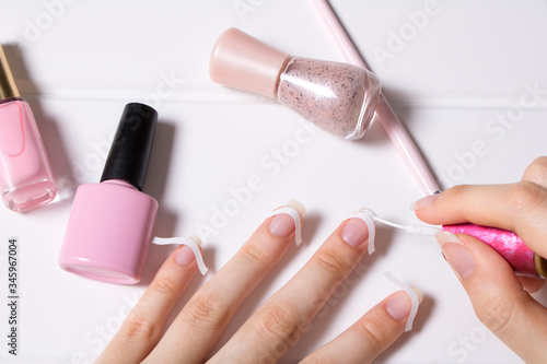 A woman does a French manicure. Skin care. The girl applies nail Polish. Nail salon, procedure, SPA. Home nail care. Manicure tools. Beauty, nail art, Glamour.