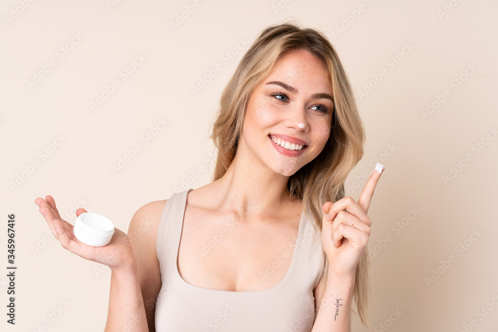 Teenager blonde girl with moisturizer over isolated background Teenager blonde girl with moisturizer over isolated background