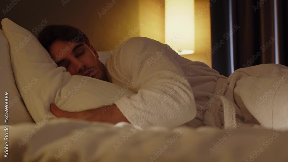 surface level of young man sleeping in bed in hotel room surface level of young man sleeping in bed in hotel room