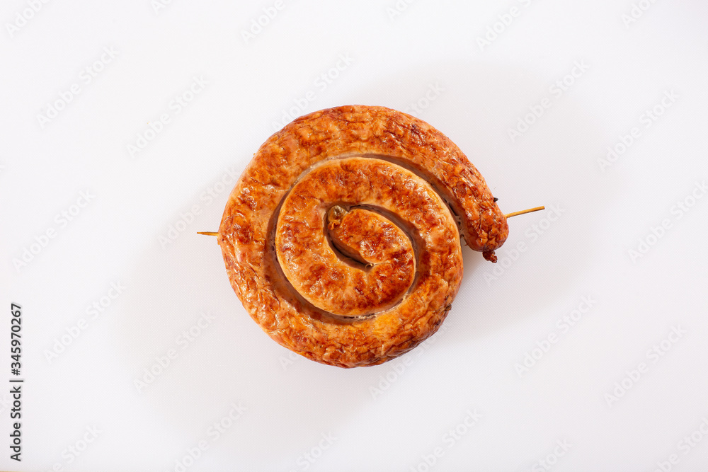 Snail sausage in traditional spiral on white background. Grilled round sausages . Delicious barbecue. There is a delicious fresh traditional village sausage in a natural shell, rolled into a snail.