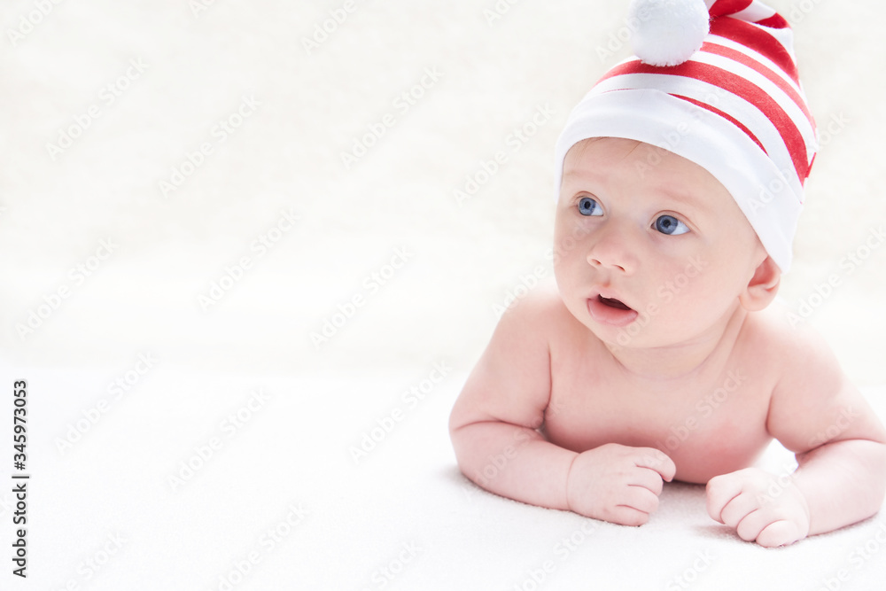 Cute little baby in christmas hat on light background
