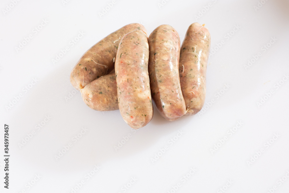 Raw pork beef sausages on white background. Traditional German homemade sausages. Delicious raw meat for barbecue. Advertising for meat shop and farm. Top view. Space for text Raw pork beef sausages on white background. Traditional German homemade sausages. Delicious raw meat for barbecue. Advertising for meat shop and farm. Top view. Space for text