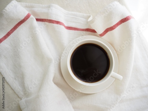 ブラックコーヒーの入ったコーヒーカップと白いリネン