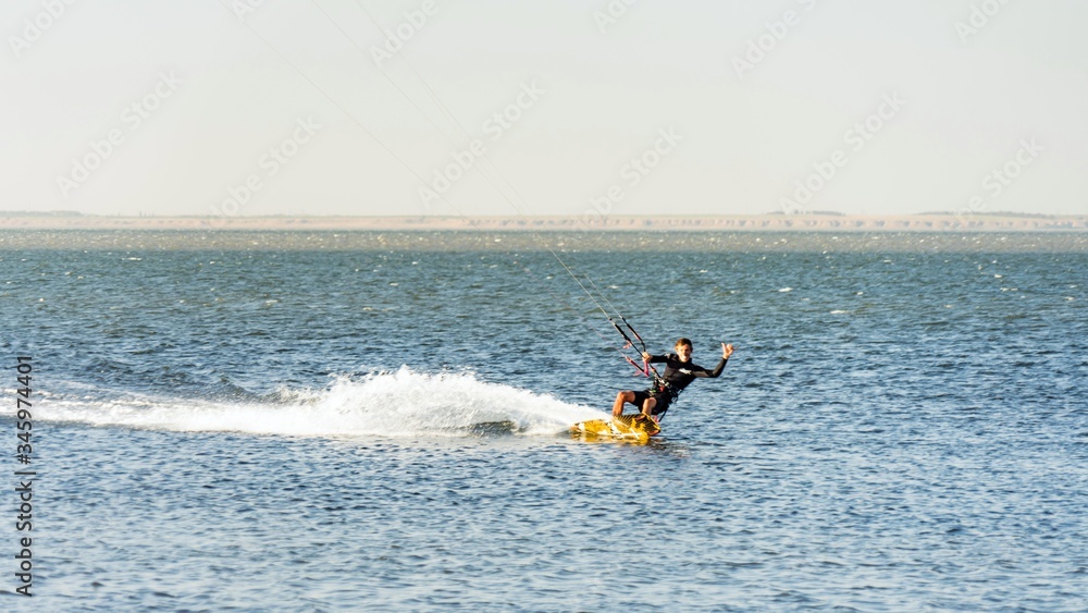 Man kitesurfer rides kite splashing at Black Sea coast on sunny day. Blagoveshenskaya. Anapa, Russia. Man kitesurfer rides kite splashing at Black Sea coast on sunny day. Blagoveshenskaya. Anapa, Russia.