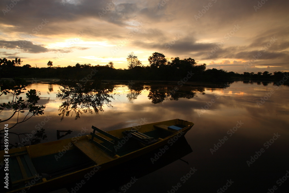 Landscape of Amazon jungle river with floating boat during sunrise  in Brazil