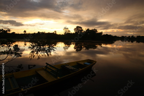 Landscape of Amazon jungle river with floating boat during sunrise in Brazil