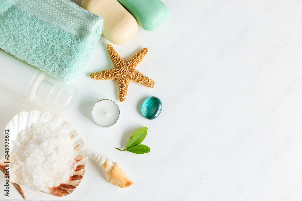 Spa cosmetics and towel with sea stars and salt in the scallop shell on a white background on top Spa cosmetics and towel with sea stars and salt in the scallop shell on a white background on top