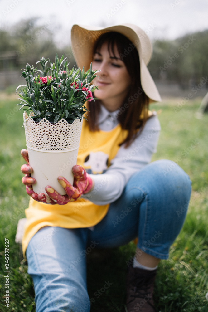 Blurred girl holding pot with flowers outdoors Blurred girl holding pot with flowers outdoors