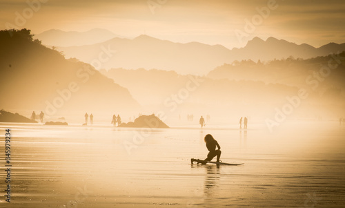 Surfista realizando estiramientos sobre la arena de la playa