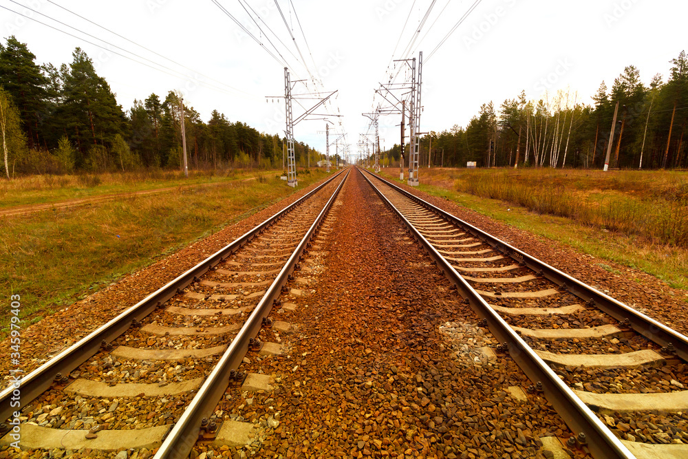 Railroad tracks going into the distance against the background of the forest and electric supports Railroad tracks going into the distance against the background of the forest and electric supports