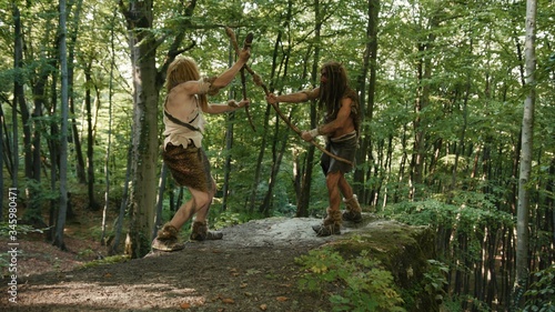 Tablou pe pânză Two persistent angry wild men fighting for tribe leadership on mountain edge in prehistoric competition in jungle forest