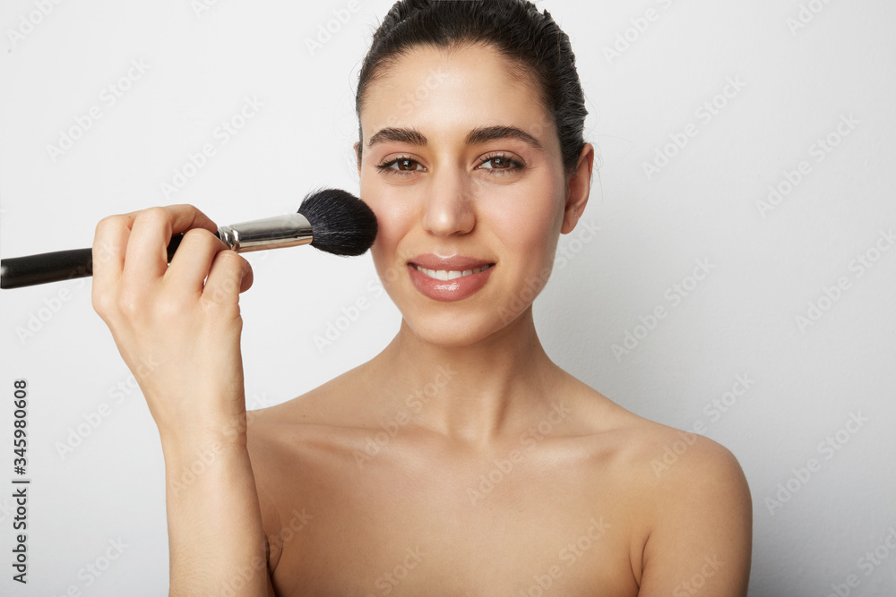 Young woman naked shoulders clean skin applying make up for a evening date in front of a camera. Space for text. Young woman naked shoulders clean skin applying make up for a evening date in front of a camera. Space for text.