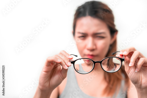 Fototapeta Naklejka Na Ścianę i Meble -  Asian woman holding glasses on white background, Selective focus on glasses , myopia and eyesight problem concept.