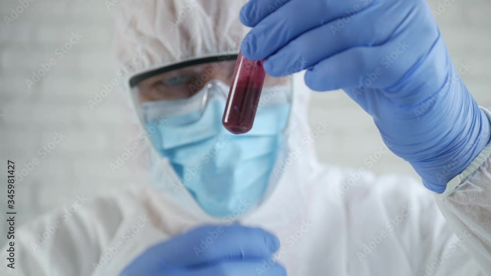 Slow Motion with a Doctor in Hospital Laboratory Wearing a Protection Suit Looking to a Tube with Blood Infected with Coronavirus Slow Motion with a Doctor in Hospital Laboratory Wearing a Protection Suit Looking to a Tube with Blood Infected with Coronavirus