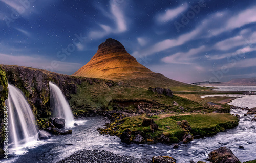 Wonderful Evening View of Kirkjufell waterfall with stars sky over the Kirkjufell mount. Scenic image of Iceland. long exposure shot. scenery of tipical Icelandic nature with Northern Lights. postcard