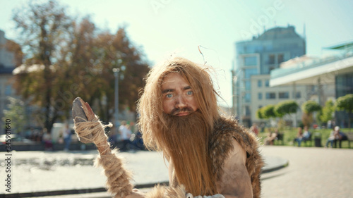 Tableau sur toile Ancient discoverer wildman in animal fur exploring future city architecture modern civilization with great surprise