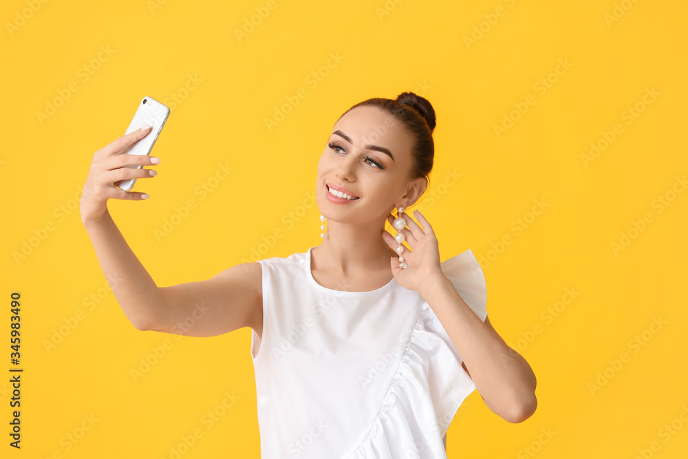 Beautiful young woman taking selfie on color background Beautiful young woman taking selfie on color background